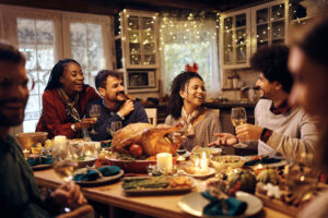 friends having fun while talking during Thanksgiving dinner at dining table.